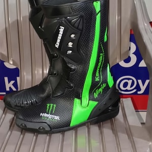 Puede incluir: Botas de moto Kawasaki Ninja negras y verdes. Las botas presentan el logotipo de Kawasaki, la palabra "Ninja" y el logotipo de Monster Energy. Las botas tienen un diseño perforado y están hechas de un material duradero.