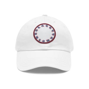 Könnte beinhalten: Weiße Baseballkappe mit einem roten und blauen runden Patch. Der Patch hat eine weiße Mitte und einen Ring aus Blau und Rot am Rand.