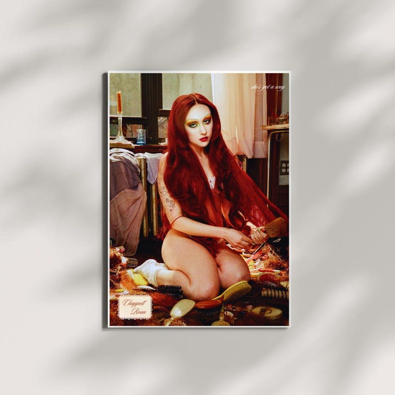 May include: A framed print featuring a woman with long red hair, seated on the floor. The image includes various hairbrushes and the text "Chopped Room" and "she's got a way". The overall aesthetic is artistic and evocative.