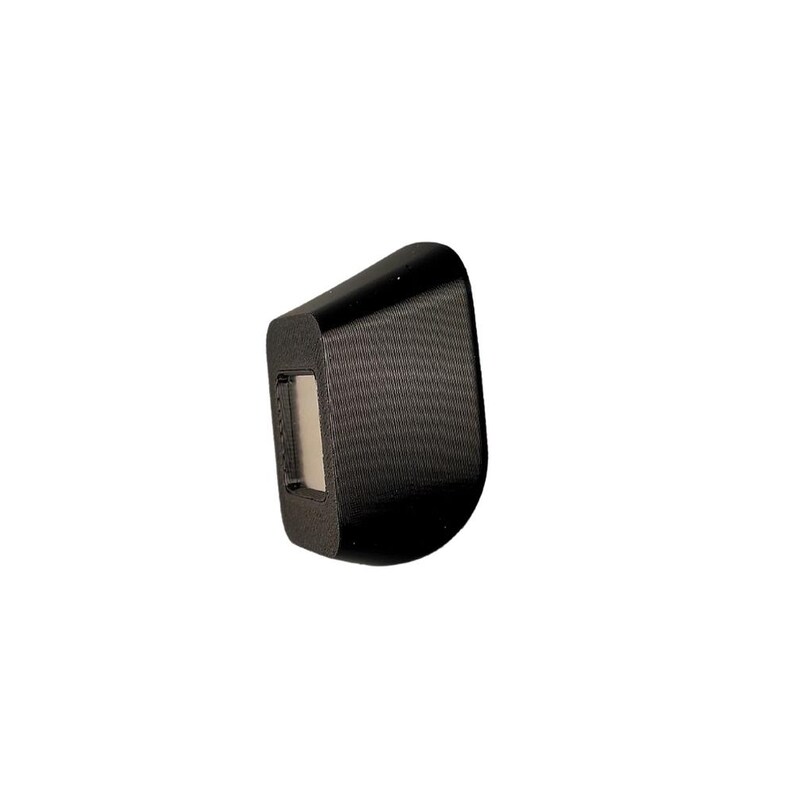 May include: A black, rectangular, textured object with a small, rectangular, light-colored opening in the center. The object is angled slightly to the right.