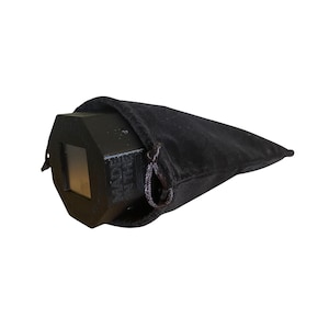 May include: A black, geometric prism with a rectangular window, partially enclosed in a black velvet drawstring bag. The text "MADE IN THE" is visible on the prism. The bag is closed with a black drawstring.