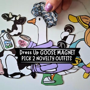 May include: A set of die-cut magnets featuring a white goose, a black and white cow, and various accessories including a purple sweater, blue hair rollers, a milk jug, a dumbbell, and a mug labeled Honk Fuel Cafe. Text reads: Dress Up GOOSE MAGNET PICK 2 NOVELTY OUTFITS.