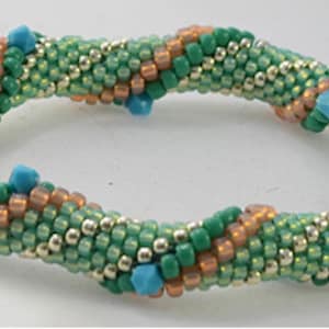 May include: A beaded bracelet featuring a spiral design. The bracelet is primarily green with accents of copper and silver beads. Small, turquoise-colored beads are evenly spaced around the bracelet, adding a pop of color. The bracelet is a handmade jewelry item.