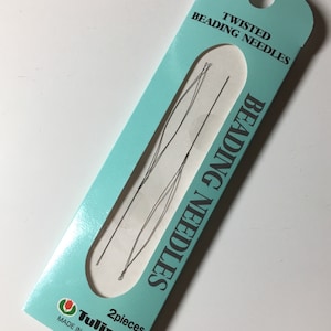 May include: A package of Tulip twisted beading needles. The package is light blue with the words "TWISTED BEADING NEEDLES" printed in white. The package also has the words "BEADING NEEDLES" printed vertically. The package contains two thin, dark needles.