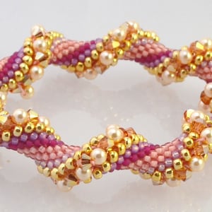 May include: A pink, purple, and gold beaded bracelet with a spiral design.
