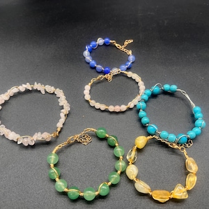 Peut inclure: Collection de six bracelets faits à la main. Les bracelets présentent diverses pierres précieuses, notamment des pierres roses, bleues, vertes et jaunes. Chaque bracelet est fabriqué avec du fil et des accents dorés.