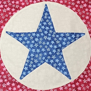 May include: A patriotic-themed fabric design featuring a large blue star filled with smaller stars on a cream-colored circle. The background is red with white and pink stars, creating a festive and decorative pattern.