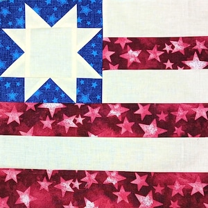 Pode incluir: Um pedaço de tecido quadrado com um desenho que se assemelha à bandeira americana. O canto superior esquerdo apresenta um campo azul com estrelas brancas e uma estrela branca no centro. Listras vermelhas alternadas com estrelas brancas e listras brancas completam o design.