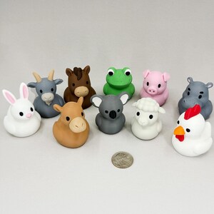 May include: A collection of ten colorful animal figurines, including a white rabbit, a gray goat, a brown horse, a green frog, a pink pig, a gray koala, a white sheep, a brown donkey, a gray hippo, and a white chicken. A U.S. quarter is included for scale.
