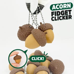 May include: A collection of acorn-shaped fidget clickers featuring brown textured caps and smooth tan bases. Each acorn is attached to a silver-colored metal ball chain. The text ACORN FIDGET CLICKER and CLICK! are visible in the image.