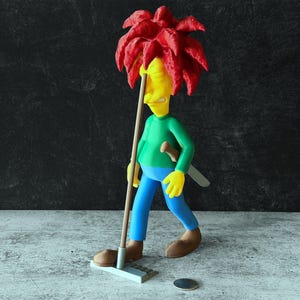 May include: A figurine of Sideshow Bob from The Simpsons, with red hair, a green shirt, blue pants, and brown shoes. He is holding a rake and a knife is tucked into his belt. A coin is on the ground.