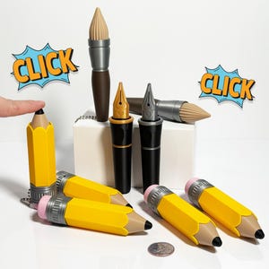 May include: A collection of novelty pens and pencils, including a brown paintbrush pen, two black fountain pens, and four yellow pencils with pink erasers. The pencils have a silver metal band around the eraser end. The pens and pencils are on a white surface with a small coin.