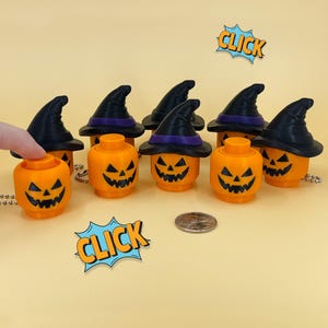 May include: Orange Halloween-themed decorations shaped like jack-o'-lanterns, each with a carved face and topped with a black witch hat with a purple band. The word "CLICK" is in a comic book style bubble.
