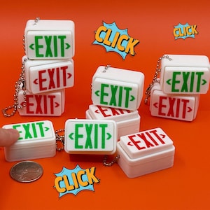 May include: A collection of white miniature EXIT sign keychains with green and red lettering. The keychains are on a silver chain and are stacked on an orange background. Comic book style "CLICK" speech bubbles are also present.