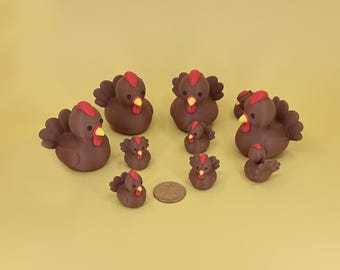 May include: A collection of brown hen and chick figurines with red combs and yellow beaks. The figurines vary in size, with several larger hens and smaller chicks. A penny is included for size reference. The background is a solid yellow.