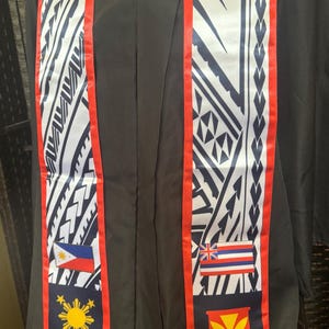 Könnte beinhalten: Eine Graduierungsstola mit rotem Besatz und einem weißen und blauen Muster. Die Stola zeigt die Flaggen der Philippinen und Hawaiis sowie das hawaiianische Symbol für den Staat.