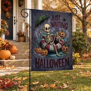 May include: A rectangular garden flag featuring a skeleton lounging in a red and white striped pool float, holding a green umbrella. The text reads JUST WAITING FOR HALLOWEEN. The scene includes three orange jack-o'-lanterns, a spider web, and ghosts.