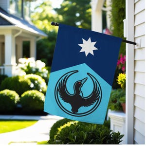 Op de afbeelding: Een decoratieve vlag voor buiten met een gestileerd vogelontwerp. De vlag heeft een donkerblauw bovenste gedeelte met een witte ster en een lichtblauw onderste gedeelte met een zwart vogel-embleem. De vogel heeft rode ogen.