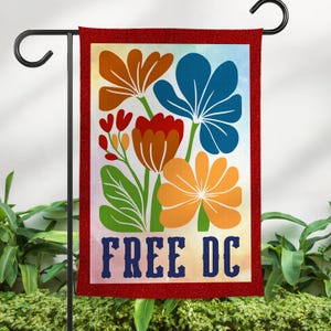 May include: A rectangular garden flag with a red border and a floral design. The design features orange, red, and blue flowers with green leaves against a colorful background. The words "FREE DC" are printed in blue at the bottom.