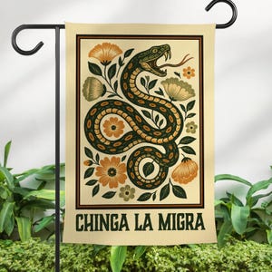 May include: A garden flag featuring a stylized illustration of a snake coiled among flowers and foliage. The snake is green and brown, with its tongue extended. The text "CHINGA LA MIGRA" is at the bottom of the flag.