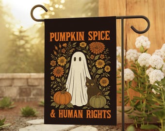 May include: Black garden flag with the text "PUMPKIN SPICE & HUMAN RIGHTS" in orange. The flag features a white ghost, black cat, pumpkins, and flowers in orange and yellow. The flag is displayed on a black metal stand.