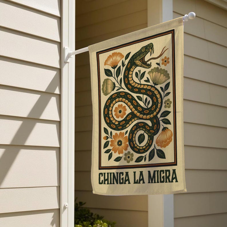 May include: A rectangular beige garden flag with a decorative snake and floral design. The snake is green and brown, with an open mouth and a long tongue. The flag has the text "CHINGA LA MIGRA" in dark green.