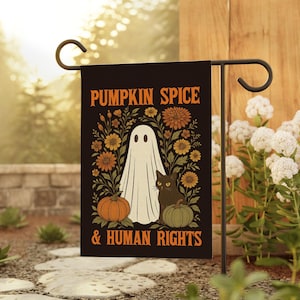May include: Black garden flag with the text "PUMPKIN SPICE & HUMAN RIGHTS" in orange. The flag features a white ghost, black cat, pumpkins, and flowers in orange and yellow. The flag is displayed on a black metal stand.