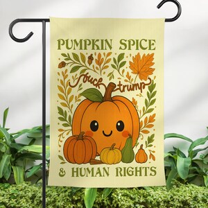 May include: A garden flag with a light yellow background features a cartoon pumpkin with a smiling face, surrounded by smaller pumpkins and leaves. The text reads "PUMPKIN SPICE" and "& HUMAN RIGHTS", with the phrase "fuck trump" in the center.
