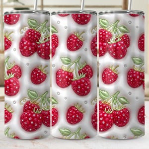 May include: A stainless steel tumbler with a repeating pattern of red raspberries with green leaves and small, sparkling accents on a white background. The tumbler has a silver lid and a straw.