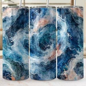 Op de afbeelding: Drie roestvrijstalen bekers met een wervelend aquarelontwerp. Het ontwerp heeft tinten blauw, wit en perzik, die lijken op oceaangolven. Elke beker heeft een zilveren deksel en een rietje.