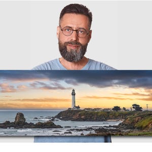 May include: A panoramic photograph of a white lighthouse on a rocky coastline with a dramatic sunset sky. The lighthouse is located on a small island with a few buildings and trees. The water is calm and the sky is a mix of orange, pink, and purple.