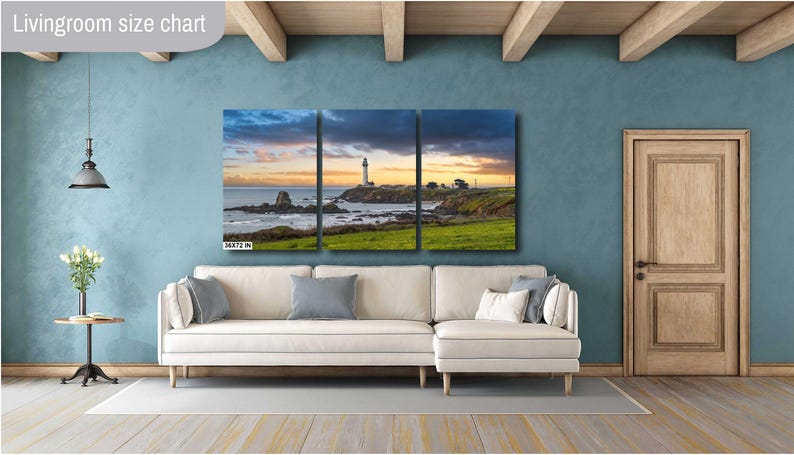 May include: A three-panel canvas print depicting a lighthouse on a rocky coastline with a sunset sky. The print is displayed on a white sectional sofa in a living room setting.