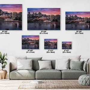 a modern living room with a gray sofa, a potted plant, and a large cityscape painting on the wall.