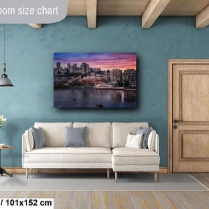 a living room with a large cityscape painting hanging on the wall above a white sofa.