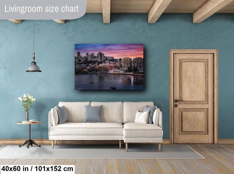 a living room with a large cityscape painting hanging on the wall above a white sofa.