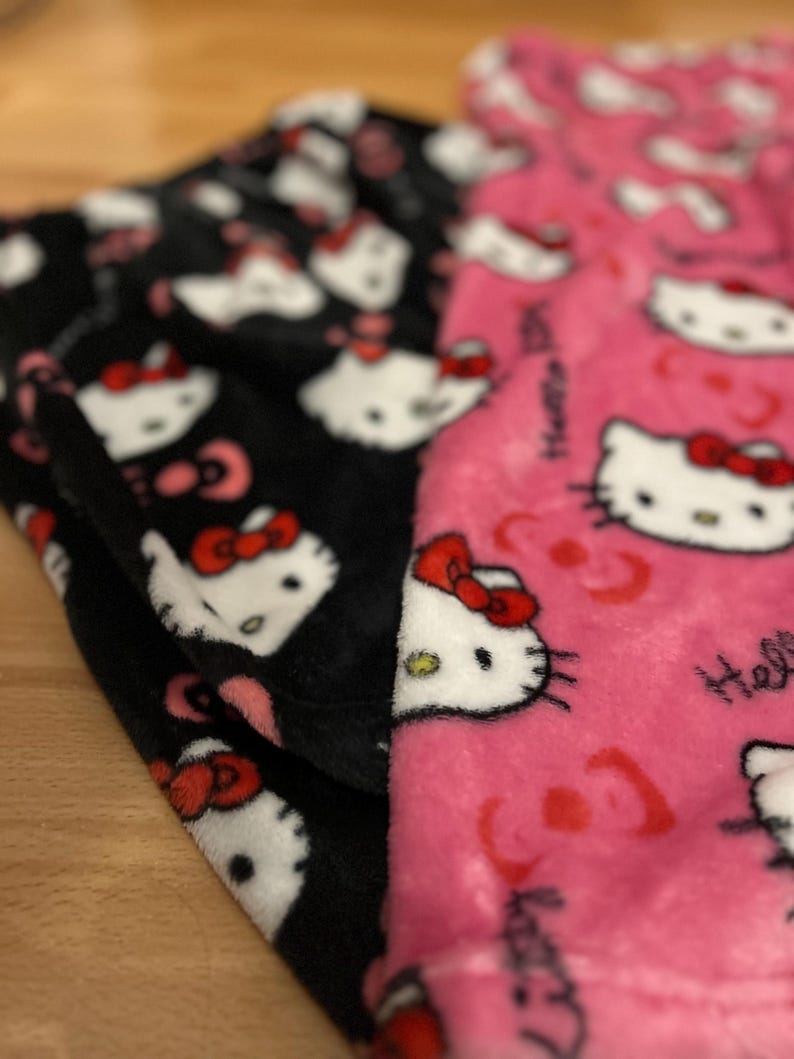 Pu&ograve; includere: Pigiama in pile nero e rosa con stampa Hello Kitty. Il pigiama presenta un lato nero con facce di Hello Kitty bianche e un lato rosa con facce di Hello Kitty bianche e il testo "Hello Kitty".