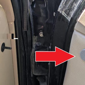 May include: Close-up of a car door interior showing a black rubber seal and a gray plastic fastener. The fastener is located near the bottom of the door frame.