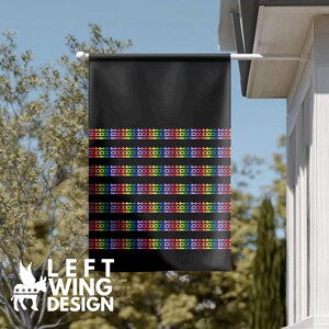 Op de afbeelding: Zwarte buitenvlag met horizontale regenboogstrepen en de tekst "BDT" herhaald. De vlag heeft ook de tekst "LEFT WING DESIGN" en een Pegasus-logo in wit.