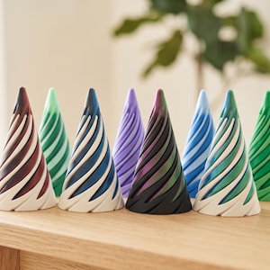 May include: A collection of nine decorative cone-shaped objects in various colors, including red, green, blue, and purple. Each cone features a spiral design with a white base, arranged on a wooden surface. The objects are likely for home decor.