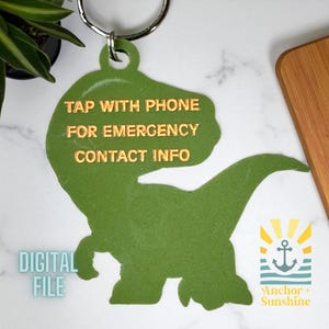 May include: Green dinosaur-shaped keychain with a silver keyring. The keychain has gold text that reads "TAP WITH PHONE FOR EMERGENCY CONTACT INFO." The words "DIGITAL FILE" are also visible. The Anchor + Sunshine logo is in the bottom right corner.