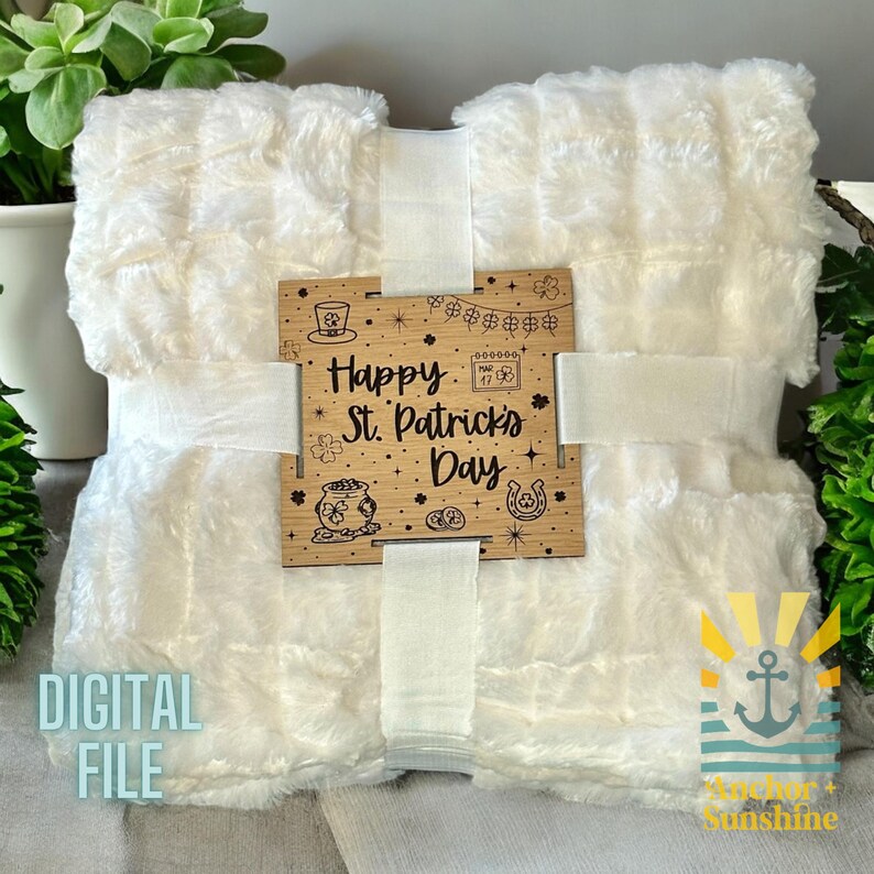 May include: A white faux fur blanket with a wooden sign that says "Happy St. Patrick's Day". The sign has a shamrock, pot of gold, and horseshoe design.