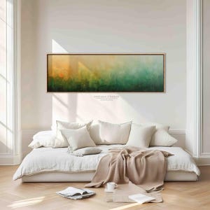 Puede incluir: Una obra de arte abstracta, larga y rectangular, con un degradado de colores de naranja a verde, cuelga sobre un diván blanco. El diván está adornado con almohadas blancas y una manta beige. El texto "DREAM FRAME CANVAS" es visible.