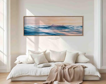 Puede incluir: Impresión en lienzo enmarcada que representa una ola del océano. La obra de arte muestra tonos azules y melocotón, con el texto "DREAM FRAME CANVAS". La impresión está sobre un sofá cama blanco con almohadas y una manta beige.