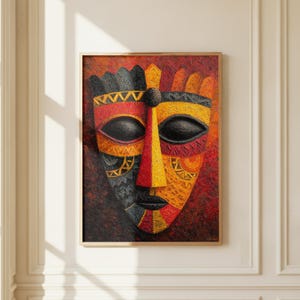 May include: Framed African mask art. The mask features a symmetrical design with black, red, and yellow colors. The mask has a textured appearance and is set against a red background. The artwork is in a wooden frame.