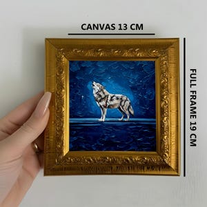 May include: A framed painting of a howling wolf under a starry night sky. The canvas measures 13 cm, and the full frame is 19 cm. The frame is ornate and gold-colored, adding a decorative touch to the artwork. The painting features a wolf in shades of gray and white.