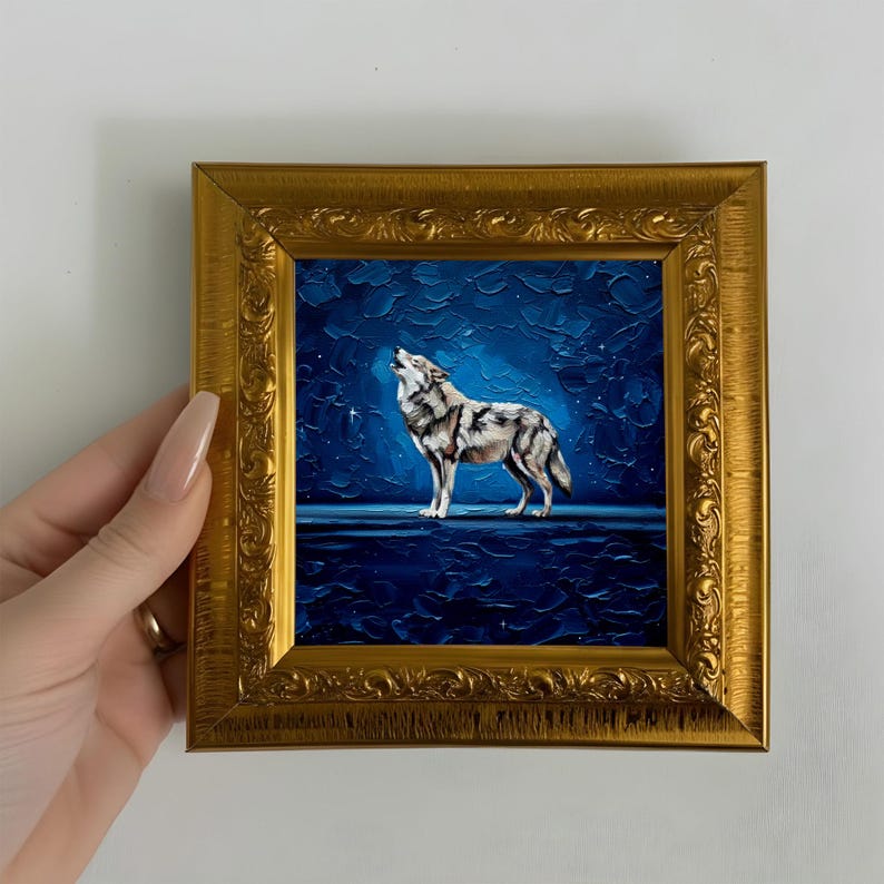 May include: A framed painting of a howling wolf under a starry night sky. The artwork features a detailed depiction of the wolf in shades of gray and white against a deep blue background. The frame is ornate and gold-colored, adding a touch of elegance.