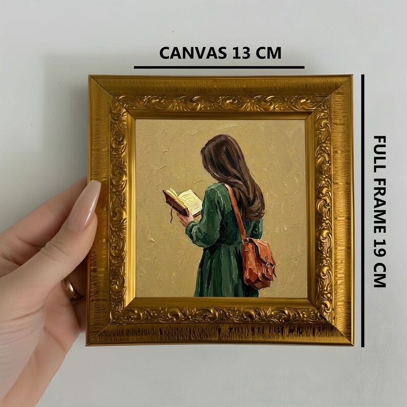 May include: A framed painting of a person reading a book, with a full frame size of 7.5 inches. The canvas is 5 inches. The painting features a woman in a green dress with a brown bag, set against a gold background and framed in gold.