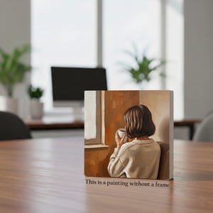 Op de afbeelding: Een kleine vierkante canvas print met een schilderij van een persoon die een mok vasthoudt en uit een raam kijkt. De schildering is in warme bruin- en beigetinten. De tekst onderaan luidt: "This is a painting without a frame."