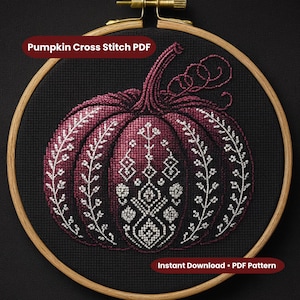 Puede incluir: Bordado de punto de cruz de una calabaza burdeos con patrones florales y geométricos blancos, sobre un fondo negro. El diseño está enmarcado en un bastidor de bordado de madera. El texto dice "Pumpkin Cross Stitch PDF" y "Instant Download • PDF Pattern."