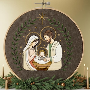 May include: A framed embroidery hoop featuring a Nativity scene. The artwork depicts Mary, Joseph, and baby Jesus, surrounded by a wreath and a star. The embroidery is in shades of brown, cream, and green, with gold accents. The hoop is displayed with candles and greenery.